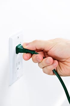 Hand pulling green electrical plug from outlet