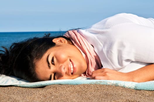 Portrait of beautiful smiling native american girl laying at beach