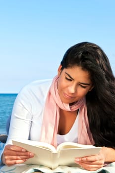 Portrait of beautiful smiling native american girl reading book at beach