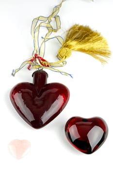 One red glass heart, one red crystal heart, and one pink quartz heart on white background.