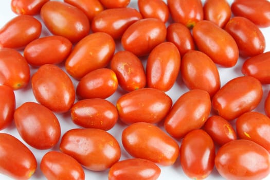 Small red organic tomatoes on a white background.