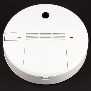 Battery powered alarm device to warn against dangerous CO buildup in indoor environments on black background.