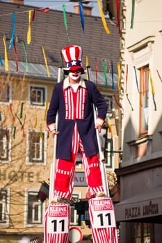 VILLACH,AUSTRIA - MARCH 5,2011: A clown on stilts took the street at the annual carnival procession held on Mar. 5,2011 in Villach,Austria. Participants come from Austria,Italy and Slovenia.