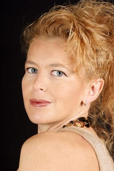 Portrait of a beautiful blond mature woman with blue eyes over a black background