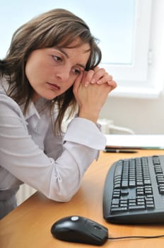 Young frustrated and depressed business person (woman) sitting at table with computer