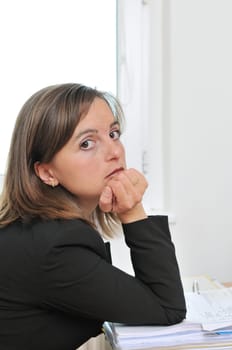 Bored business woman sitting at table with papers on workplace
