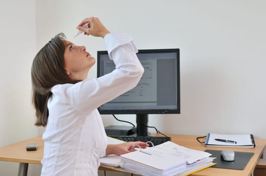 Detail of young business person (woman) applying eye drops on workplace - computer on table