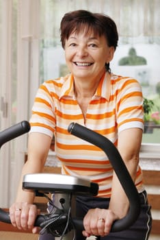Mature woman exercise on spinning bicycle at home