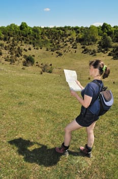 Young woman in nature looks to map and wants to find way