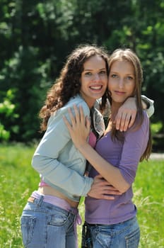 Two happy teenage friends embracing together  are outdoors in nature