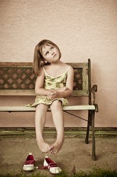 Outdoors portrait of small cute child with hanging legs - sepia tone