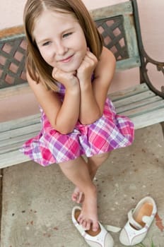 Portrait of cute smiling child sitting on bench - wall in background