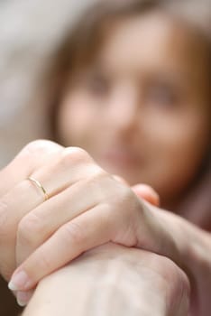One hand holds another and helps woman whose face is blurred in background
