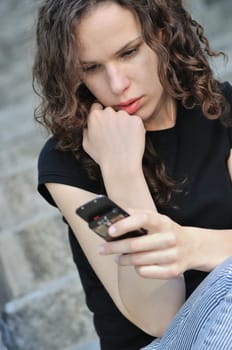 Young depressed woman (teenager) reading message on mobile phone - detail