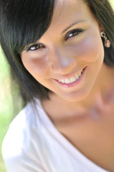 Portrait of young beautiful smiling woman with black hair - outdoors