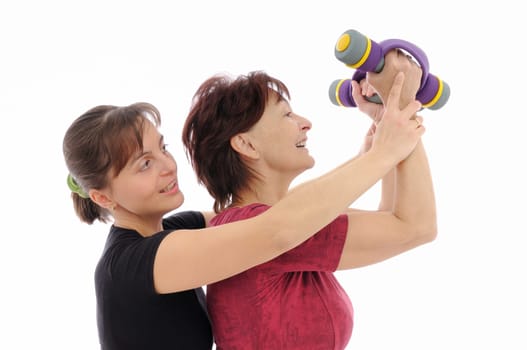 Senior woman  exercising with barbells assisted by trainer