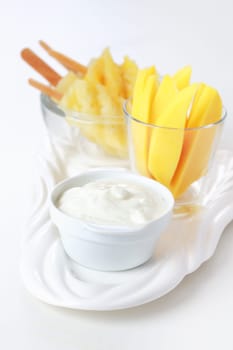 Healthy snack - Pineapple skewer with mango stripes and curd cheese or yogurt