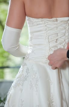 Woman helping to put wedding dress on
