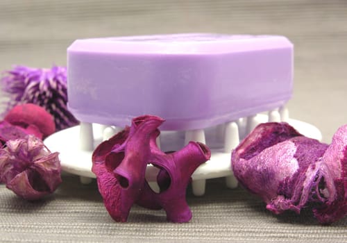 Purple soap with decorative items against gray background