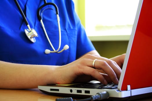 Doctor sitting at his desk with laptop computer