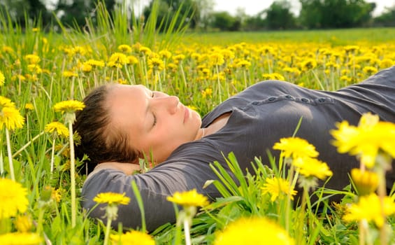 Young woman lying on a flower meadow