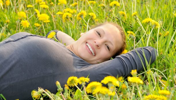 Young woman lying on a flower meadow