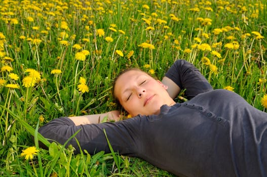 Young woman lying on a flower meadow