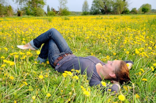 Young woman lying on a flower meadow