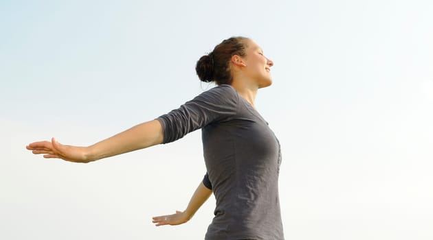 Happy young woman spreads her arms