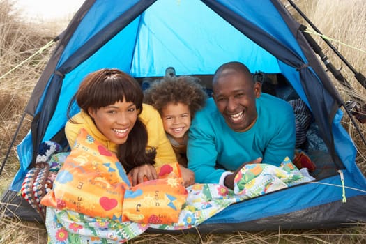 Young Family Relaxing Inside Tent On Camping Holiday