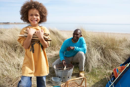 Father And Son Collecting Firewood On Beach Camping Holiday