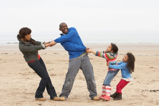 Family Having Fun On Winter Beach