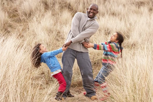 Father And Daughters Having Fun In Sand Dunes