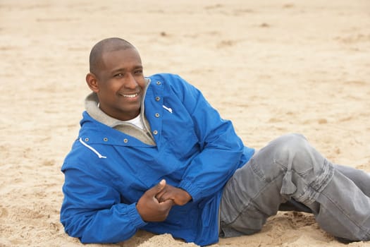 Man Relaxing On Beach In Autumn Clothing