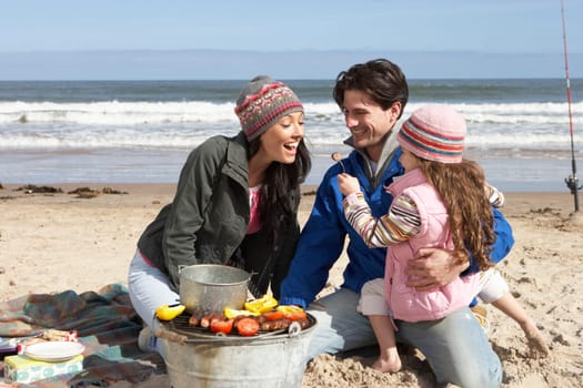 Family Having Barbeque On Winter Beach