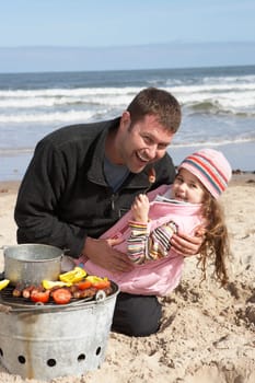 Father And Daughter Having Barbeque On Winter Beach