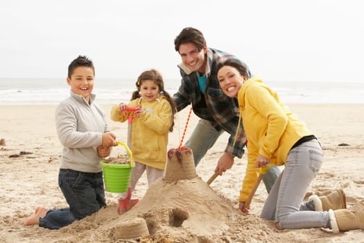Family Building Sandcastle On Winter Beach