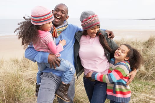 Family Walking Along Dunes On Winter Beach