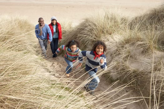 Family Walking Along Dunes On Winter Beach
