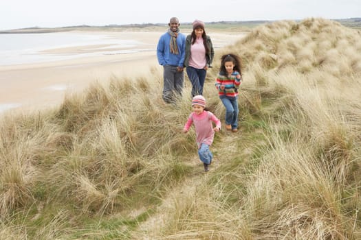 Family Walking Along Dunes On Winter Beach