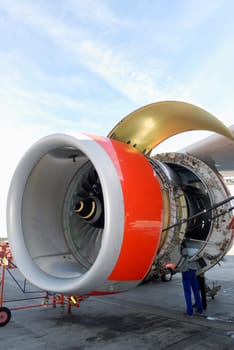 mechanic servicing large jet engine on airport ground
