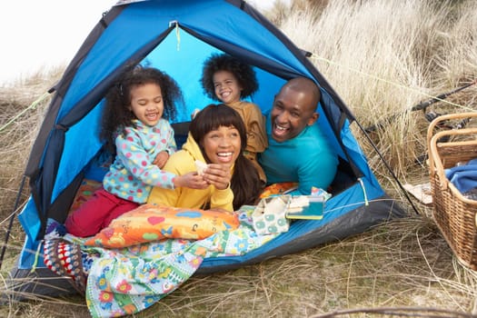 Young Family Relaxing Inside Tent On Camping Holiday
