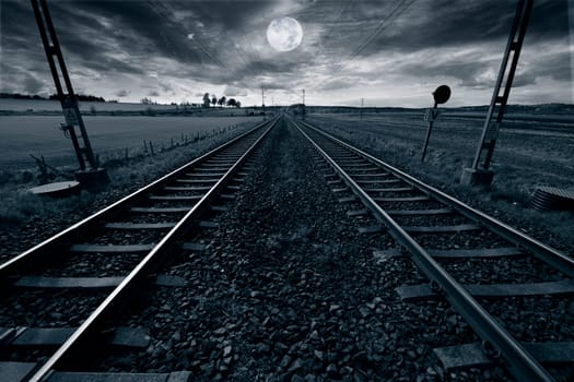 full-moon, casting moonlight over a lonely train-track, stretching into horizon
