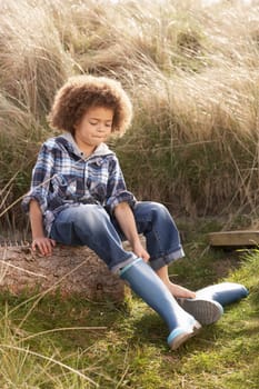 Young Boy Putting On Wellington Boots