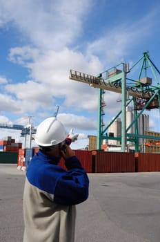port worker directing container-crane, inside busy commercial container-port