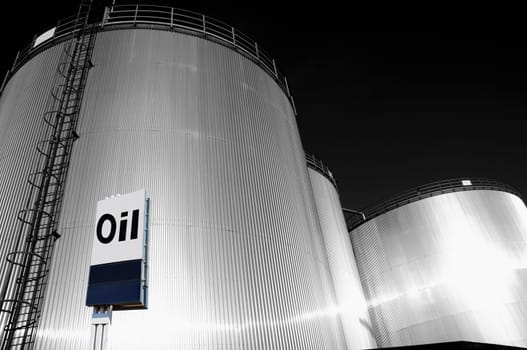 large fuel-tanks, towers with commercial sign in foreground, dark silver duplex toning concept