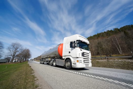 fuel-truck in speedy motion, blurred, driving on scenic highway, ground level perspective