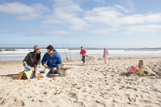 Family Having Barbeque On Winter Beach