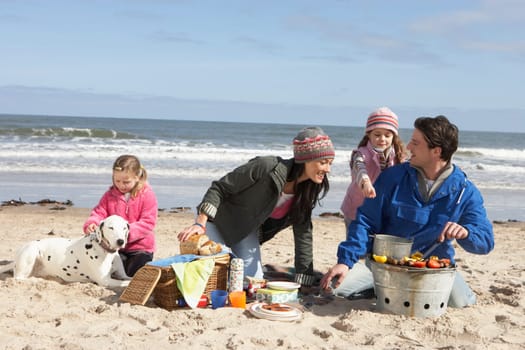 Family Having Barbeque On Winter Beach