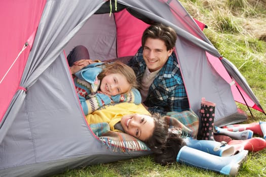 Young Family Relaxing Inside Tent On Camping Holiday